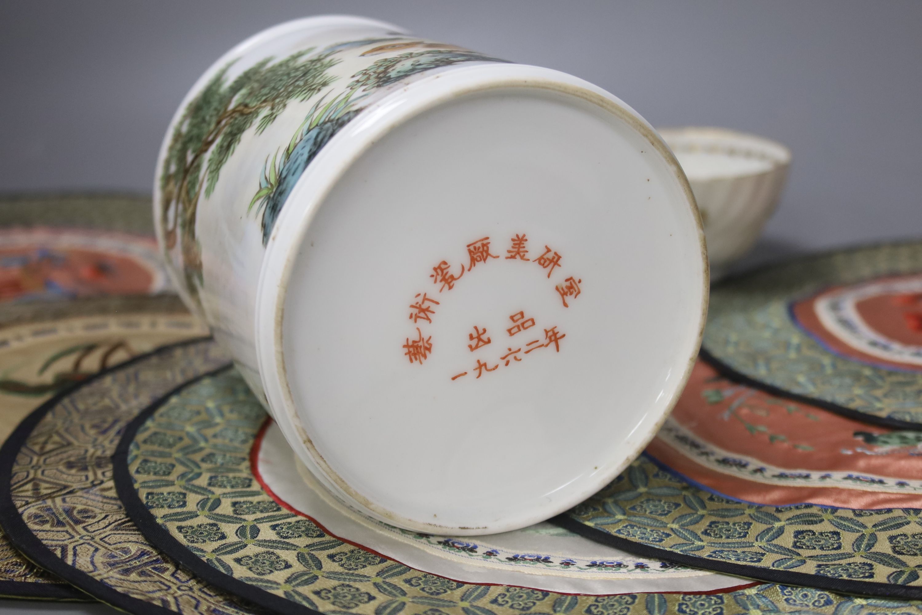 A Chinese porcelain brush pot, various embroidered silk mats etc.